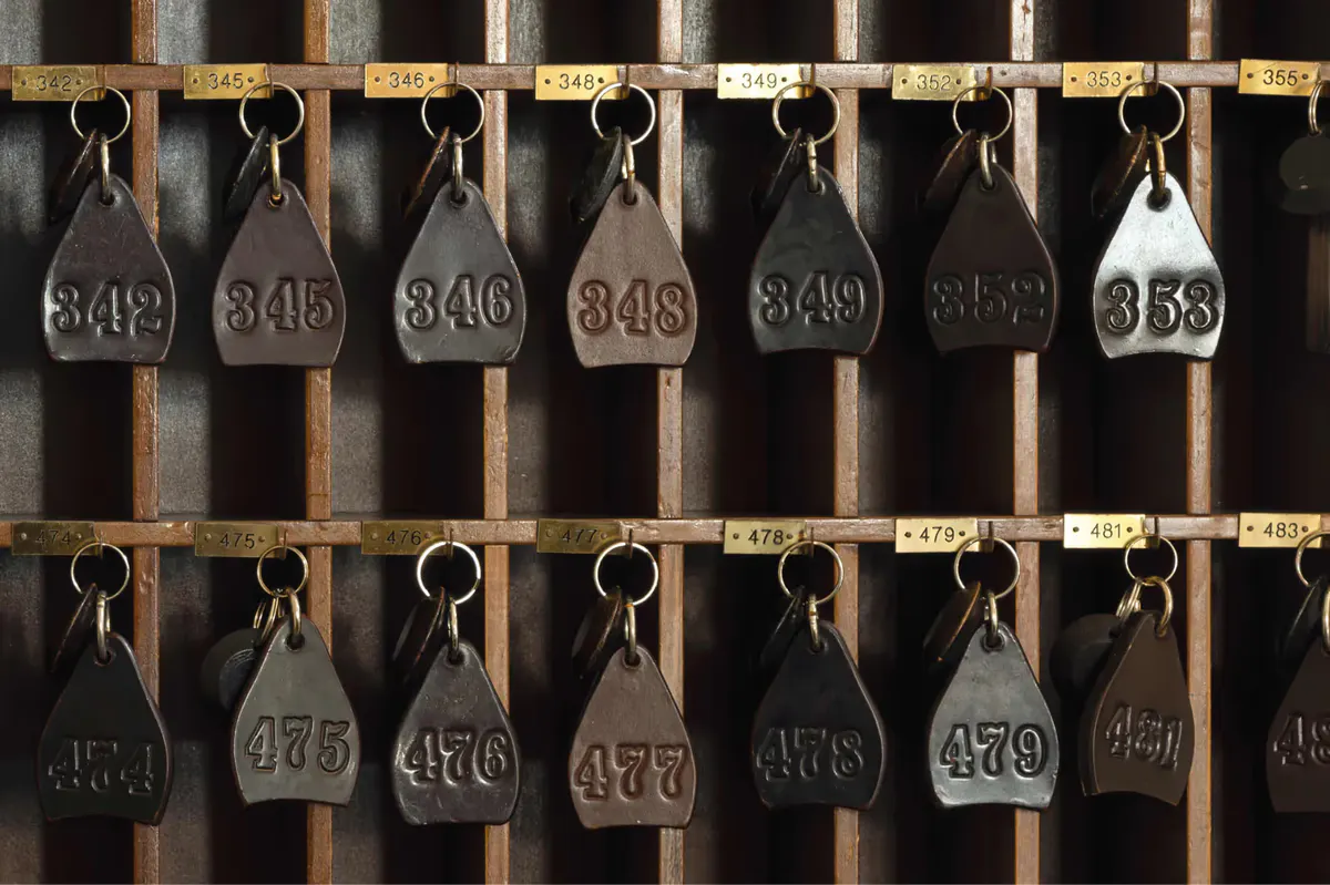 Numbered brass tags on iron hooks arranged in rows on a wooden board