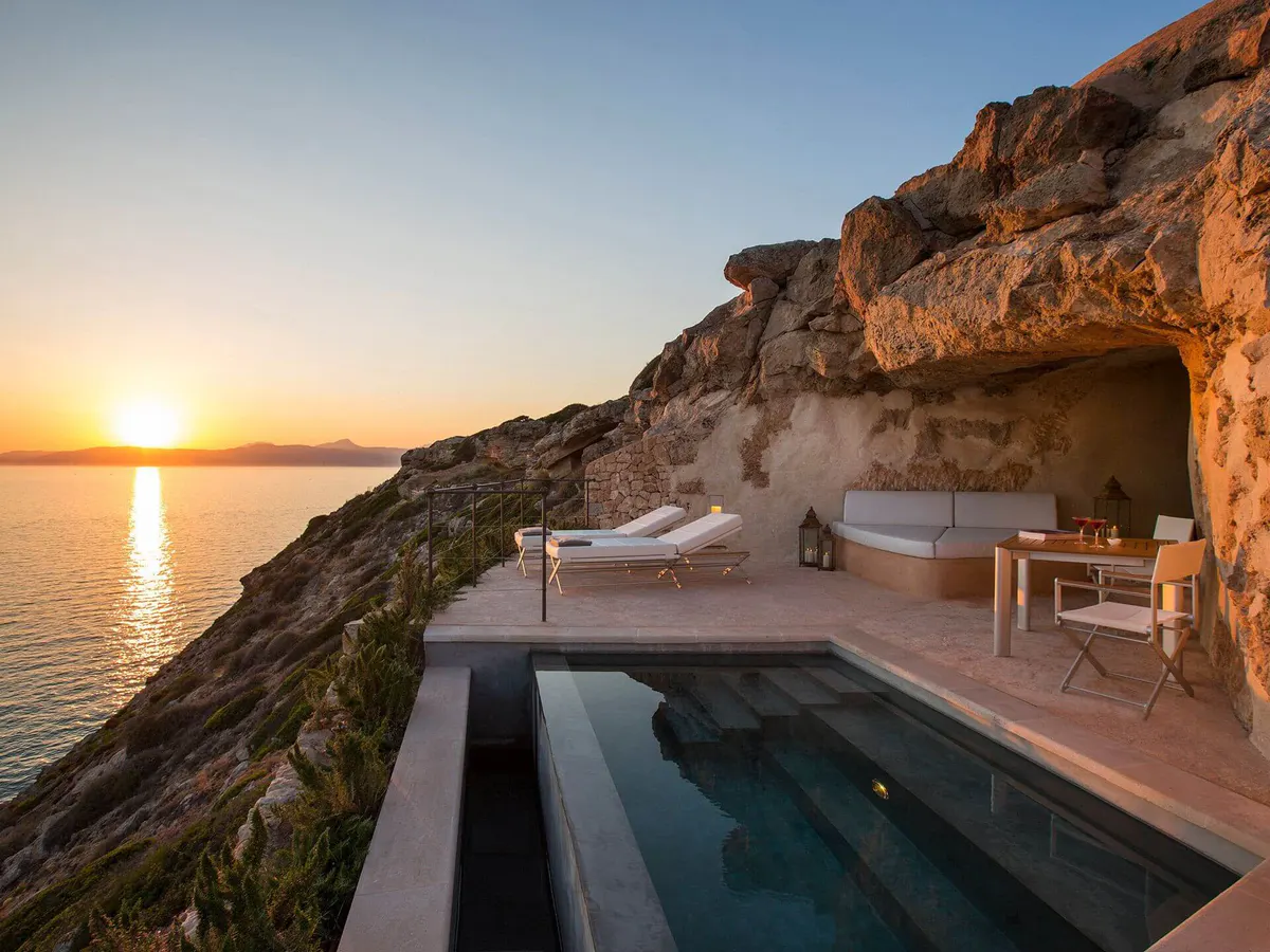 A wooden pergola frames a clear seascape, with dappled sunlight striping the view