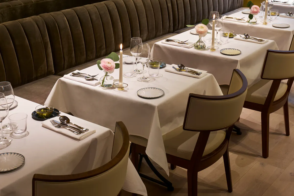 Dining room with curved banquette seating, neutral linens, and elegant table setup