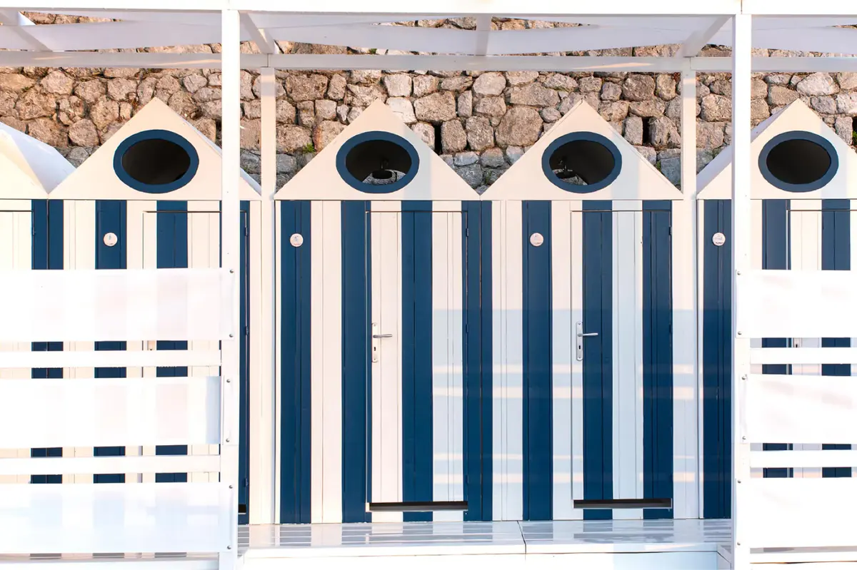 Striped beach cabanas with dark blue and white panels lining the waterfront