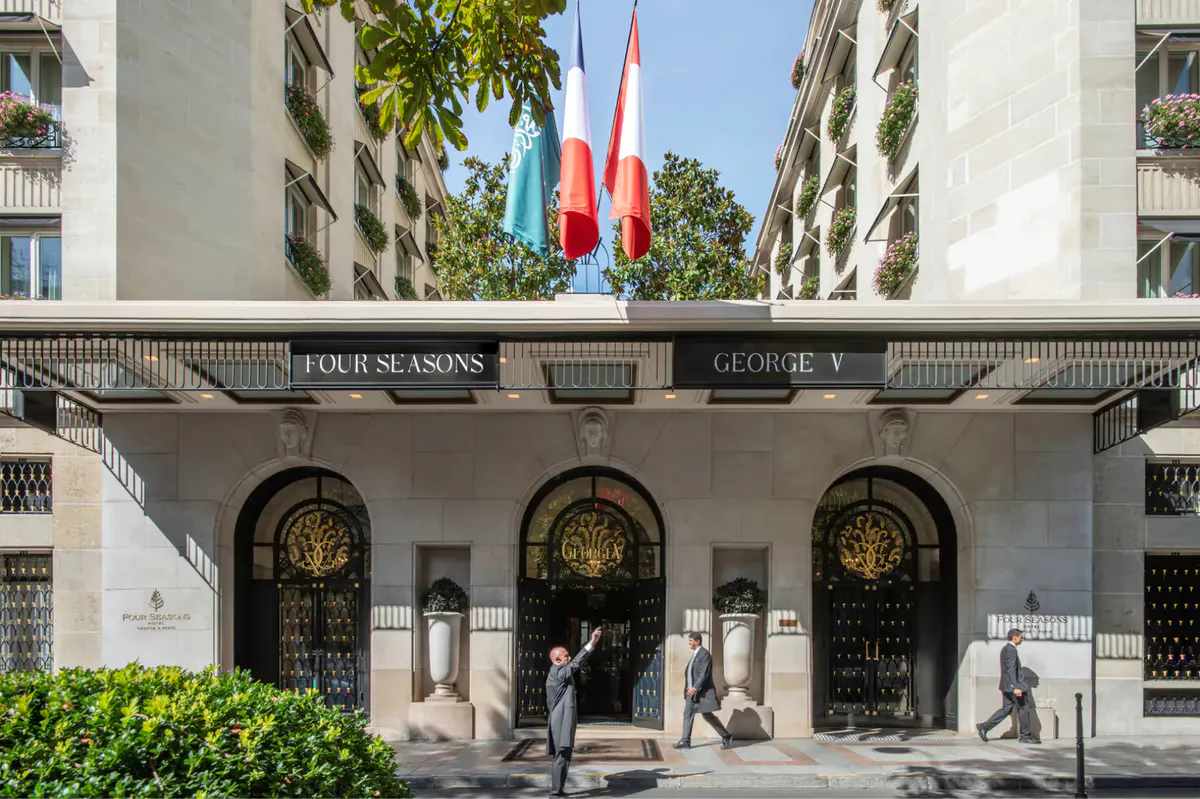 The grand entrance facade with three rounded archways and tourists at street level
