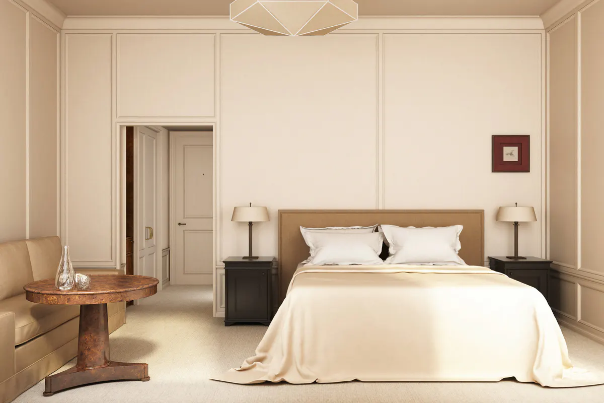A spacious bedroom with cream walls, a wood bed frame, and high ceiling