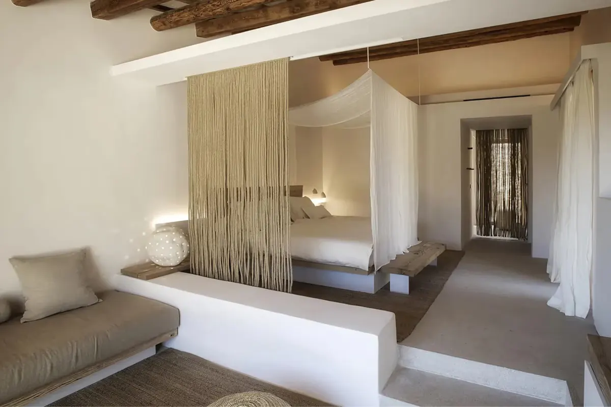 Bedroom with wooden partition wall separating sleeping area, beamed ceiling, and natural light