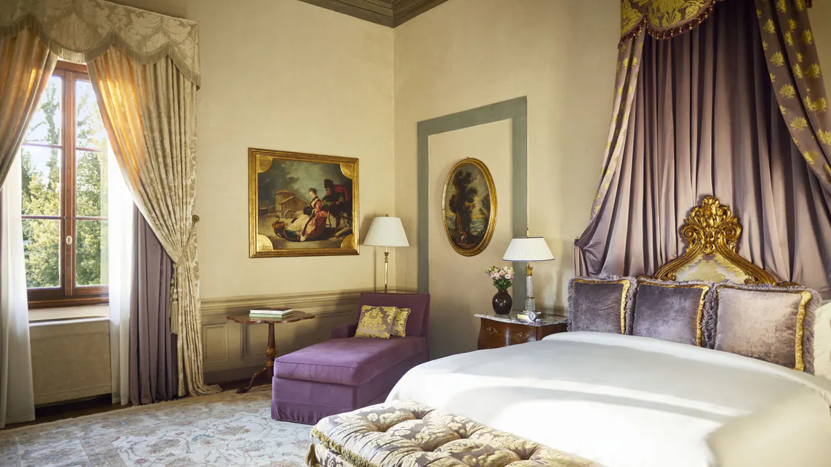Bedroom with sage walls, pale wood ceiling, classical oil paintings, and purple velvet accent chair