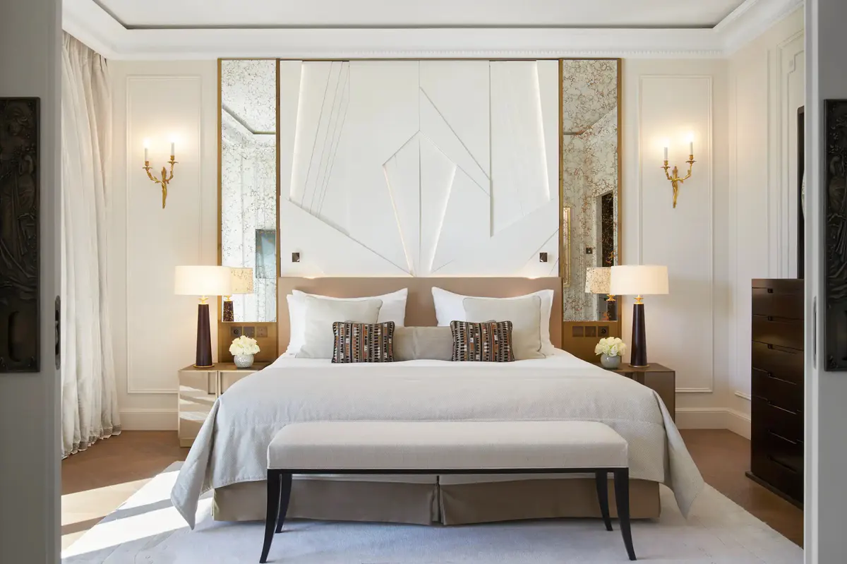 Bedroom with white upholstered headboard, wood nightstands, gold wall sconces