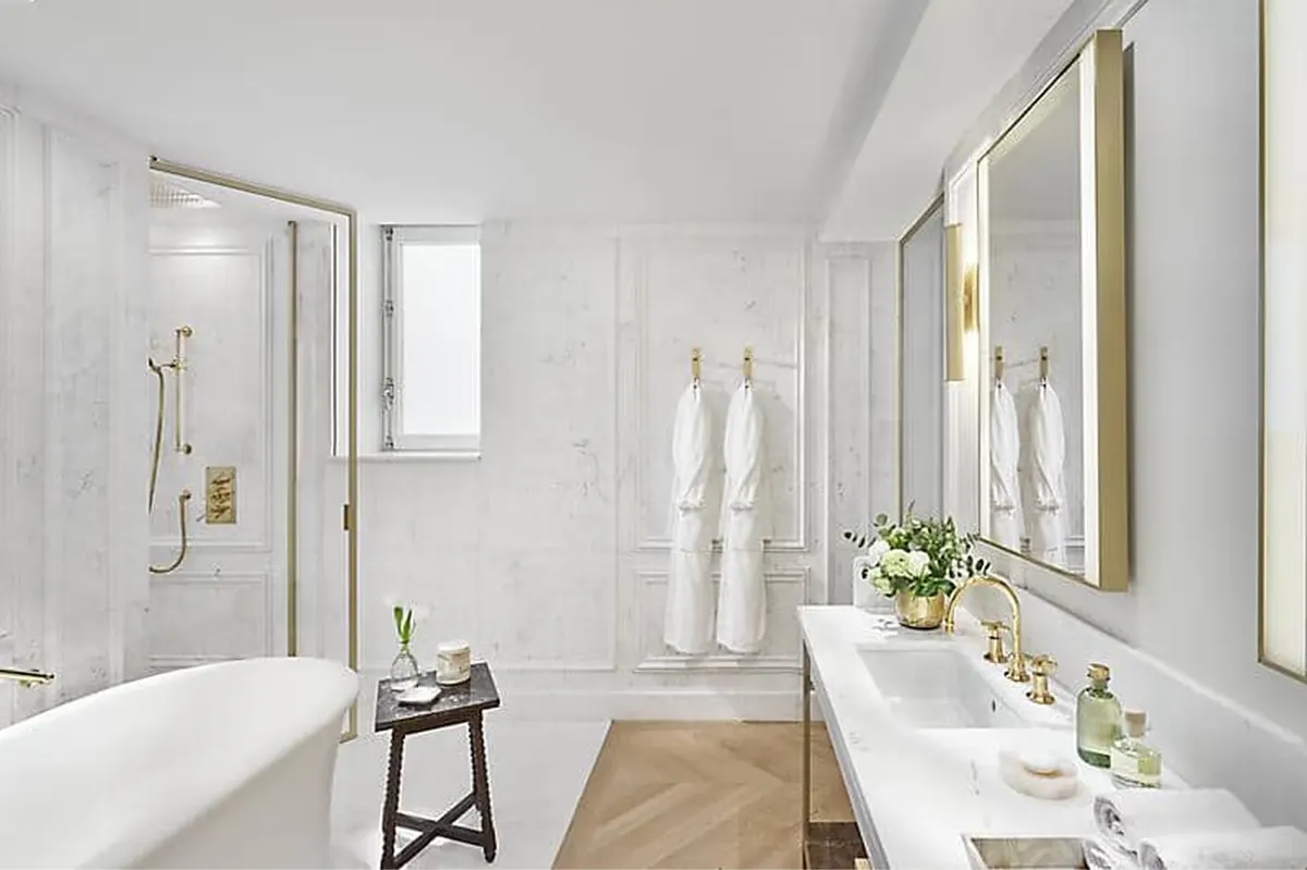 Modern bathroom with freestanding tub, white tiles, and brass fixtures