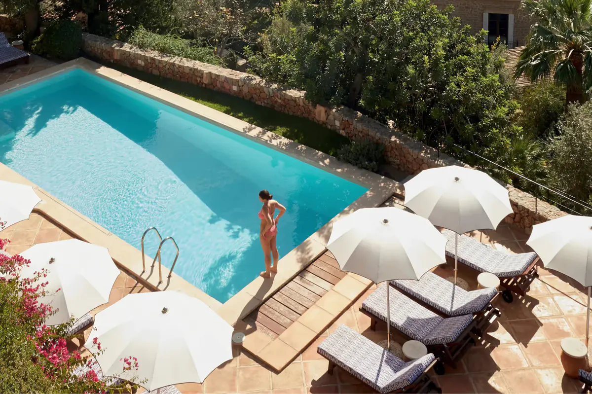Swimming pool with lounge chairs, white umbrellas, and stone building in background