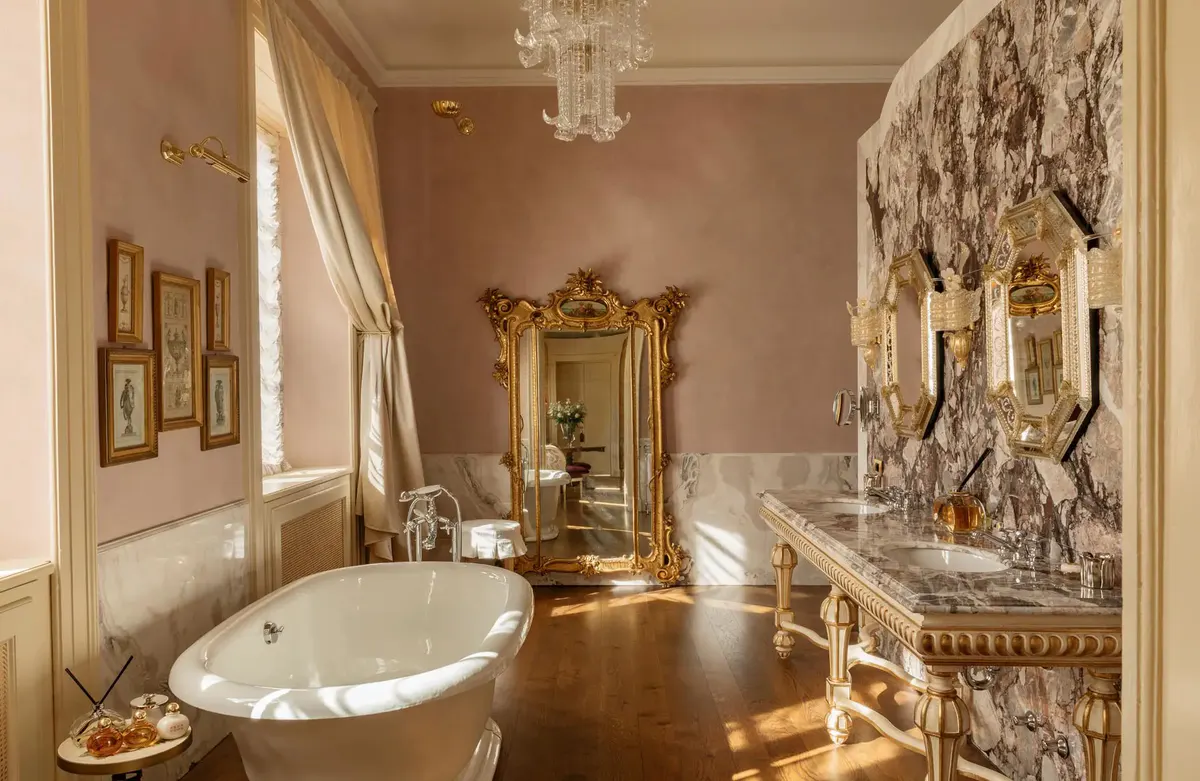 A bathroom with pink walls, freestanding soaking tub, and ornate marble details