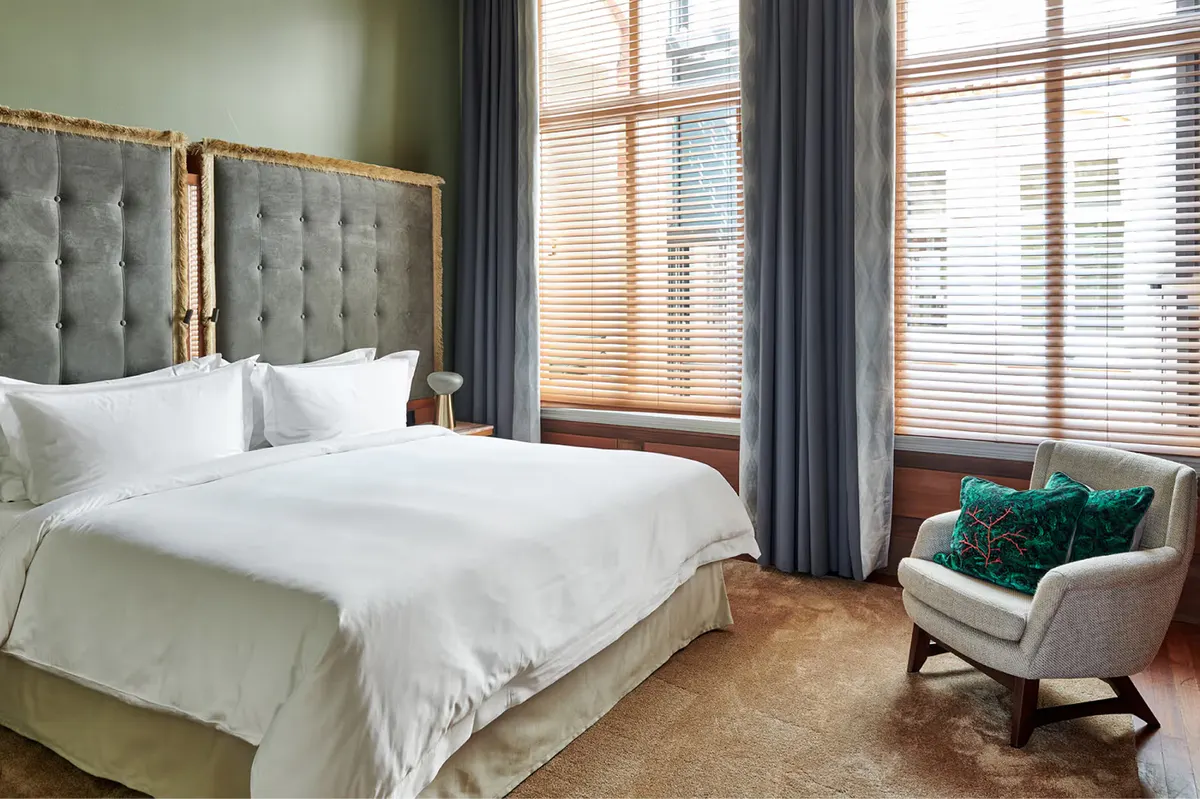 Bedroom with sage green walls, light upholstered seating, and tall windows with river views