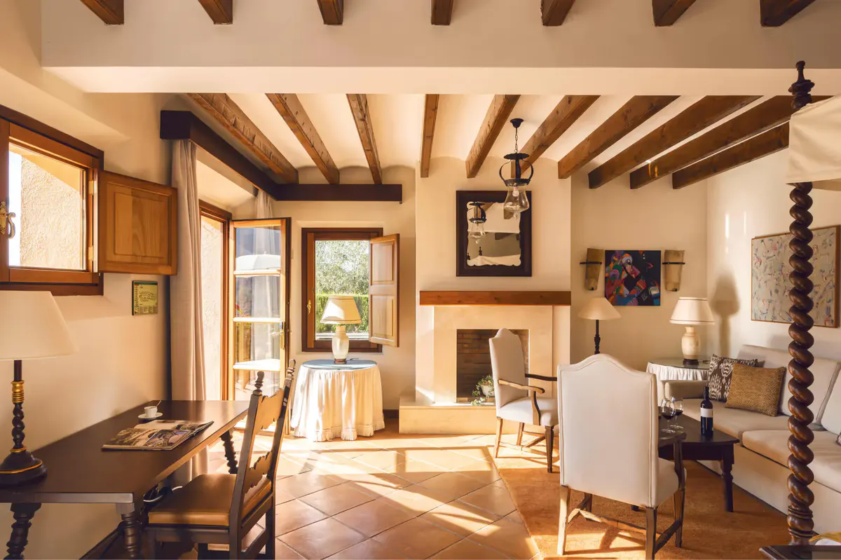 Suite interior with exposed beams, wooden doors, and sunlight streaming through open windows