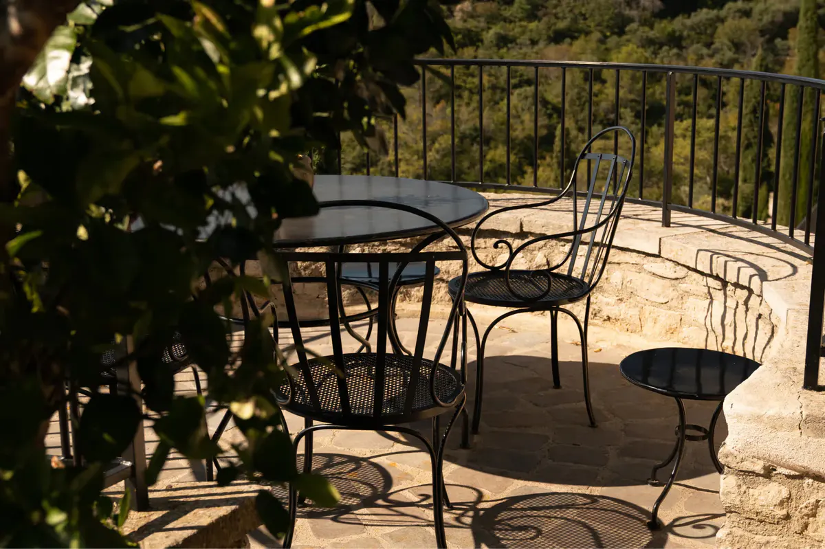 Outdoor seating on stone terrace framed by shadows and greenery