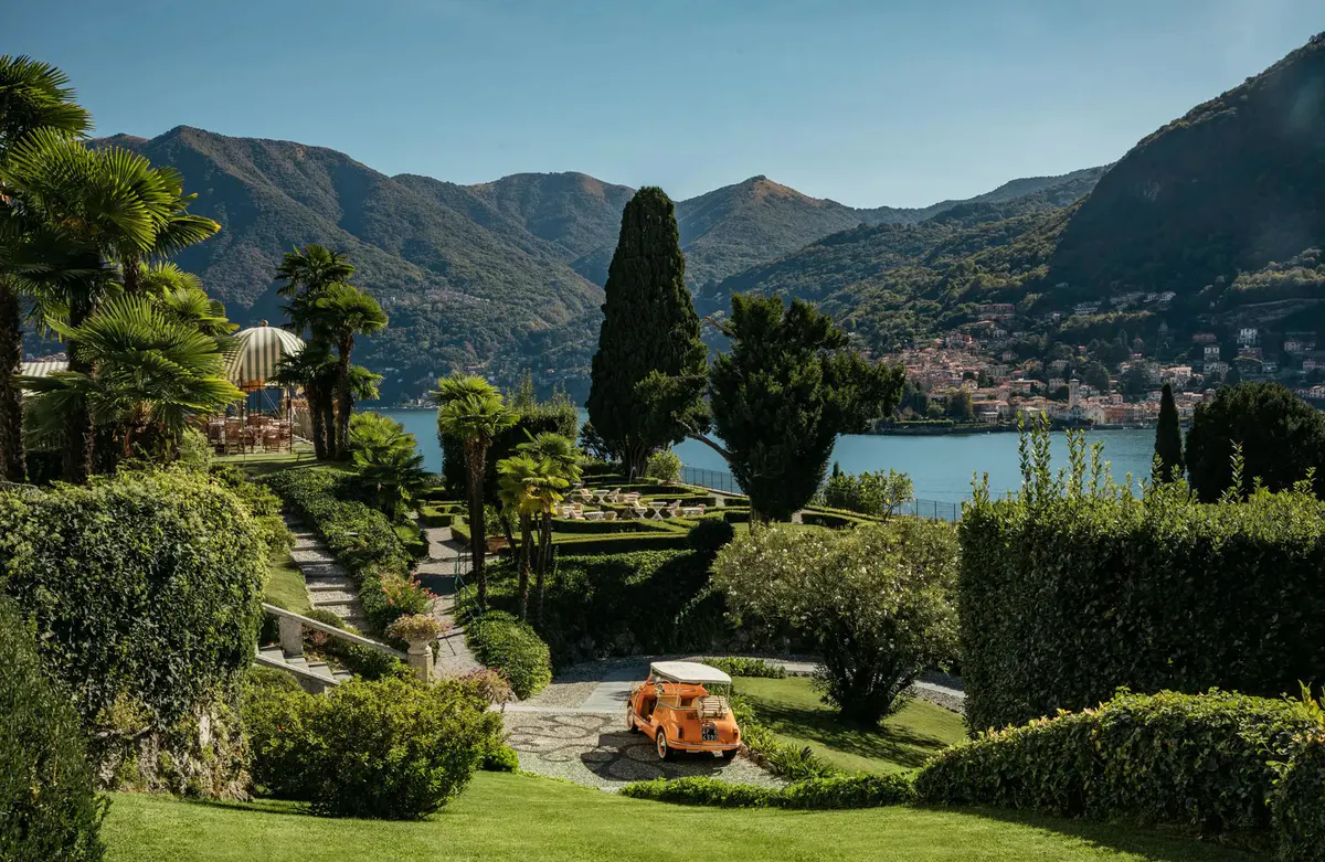 Terraced gardens with tall cypress, lawn furniture, and lake mountains in distance