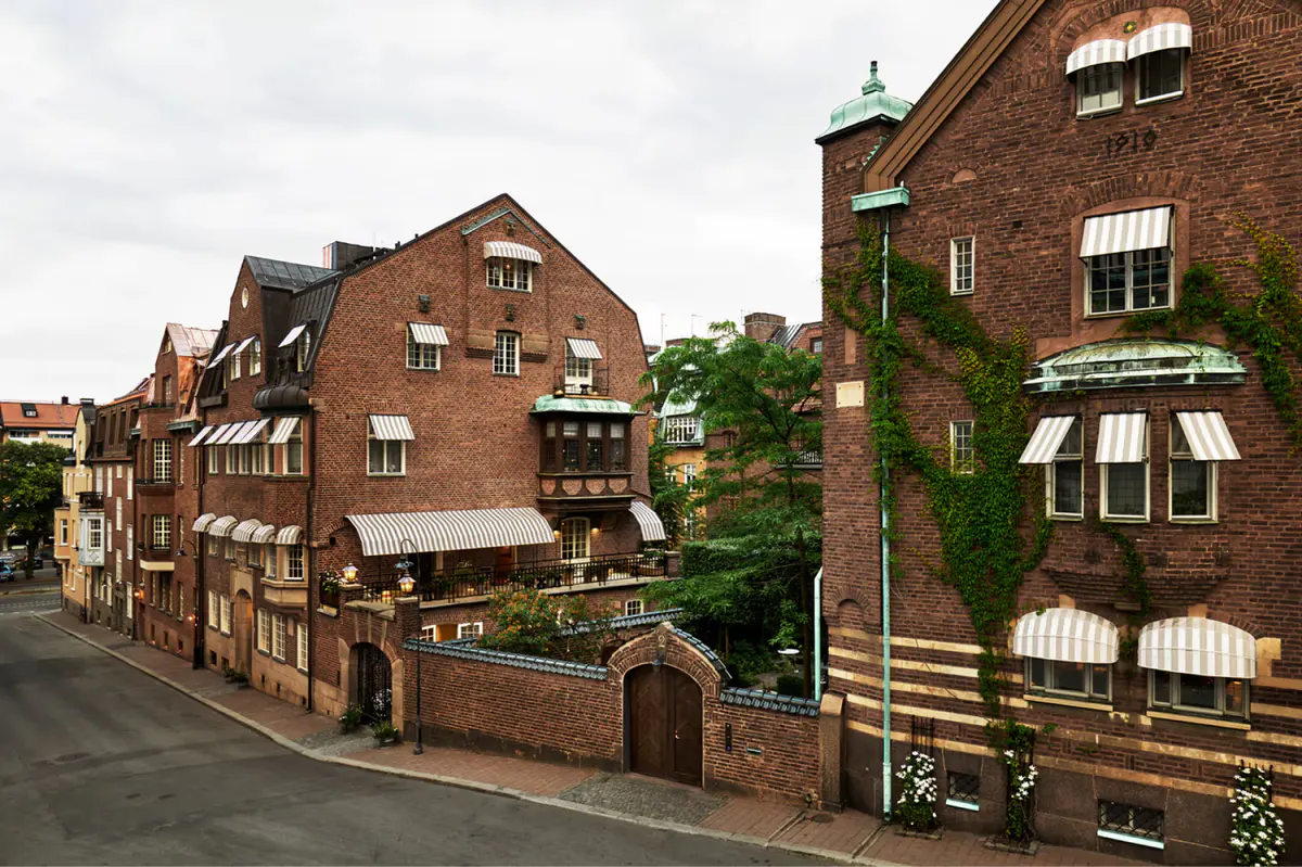 Red brick townhouses with windows, hedges, and winding street in Stockholm residential area
