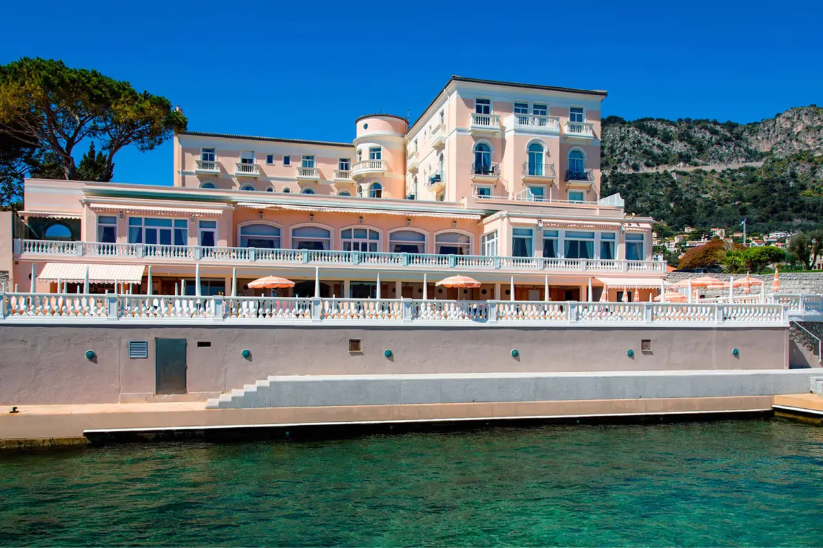 Pale stone facade of the historic hotel at waterfront with sailboats anchored nearby