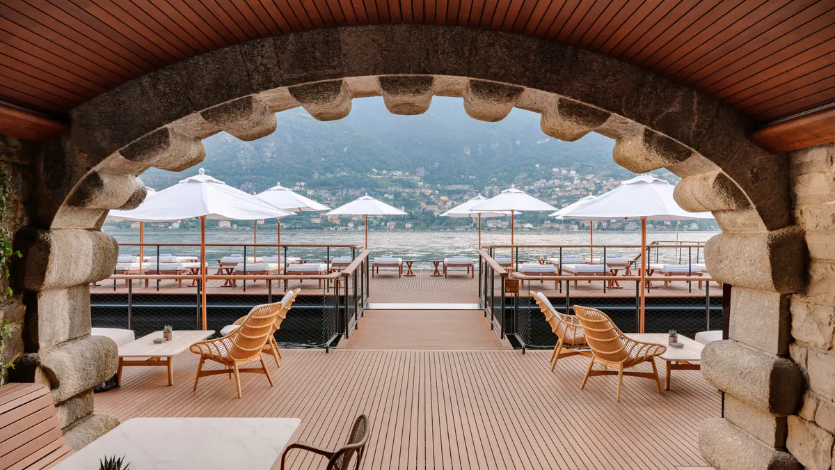 Arched wooden ceiling dining space with tables facing open terrace and lake vistas