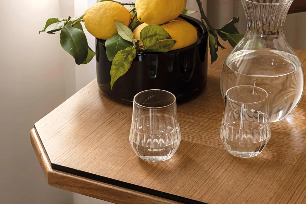 Lemons in dark bowl with glassware