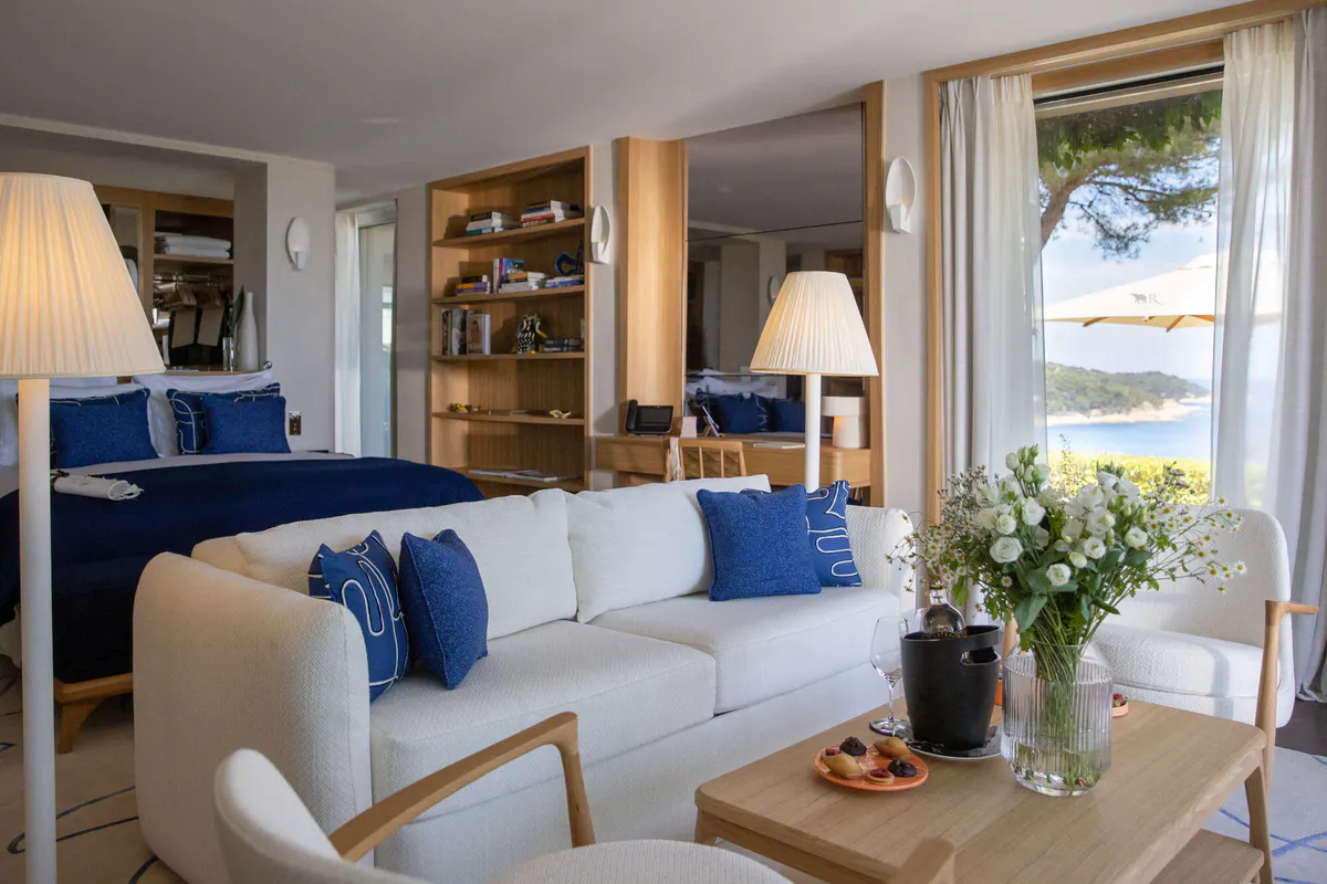 Modern suite with cream sofa and blue accents overlooking blue water