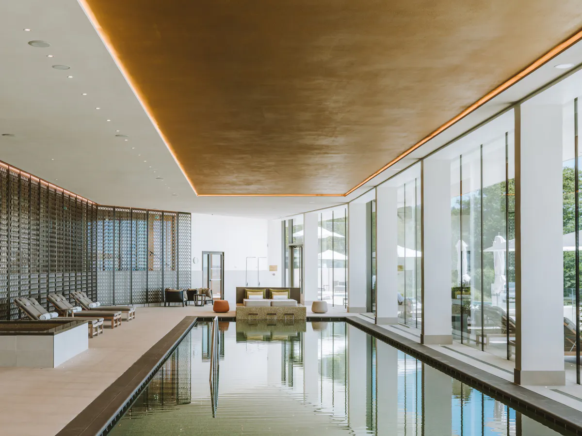 Spa with indoor pool reflecting large windows, timber walls, and natural light throughout