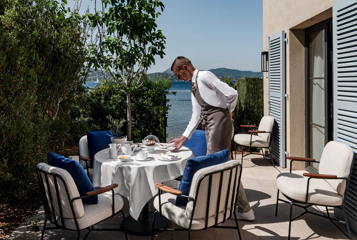 Server pouring wine at an outdoor table with coastal backdrop