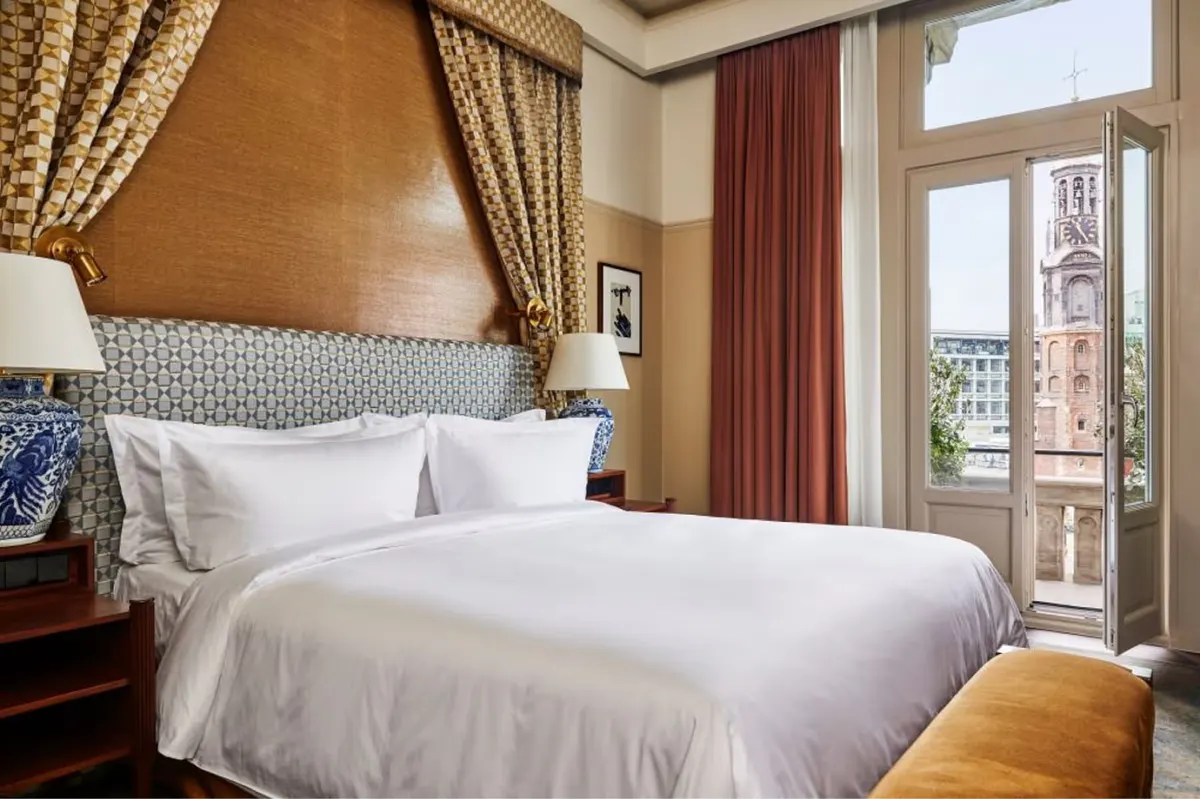 Suite bedroom with multiple seating areas and city views through large windows
