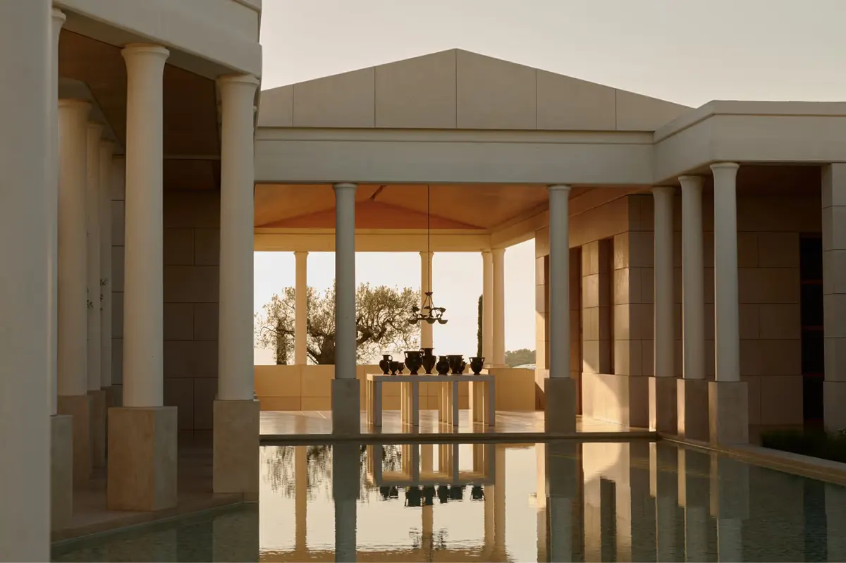 Minimalist pavilion with marble columns reflected in still water