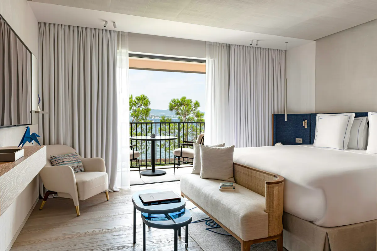 Suite with neutral palette, two beds, and terrace with tree views