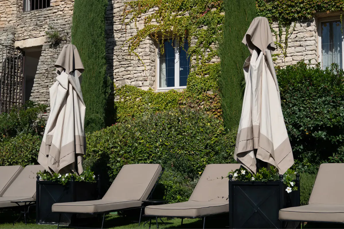 Stone terrace with closed umbrellas and lounge chairs beside stone walls