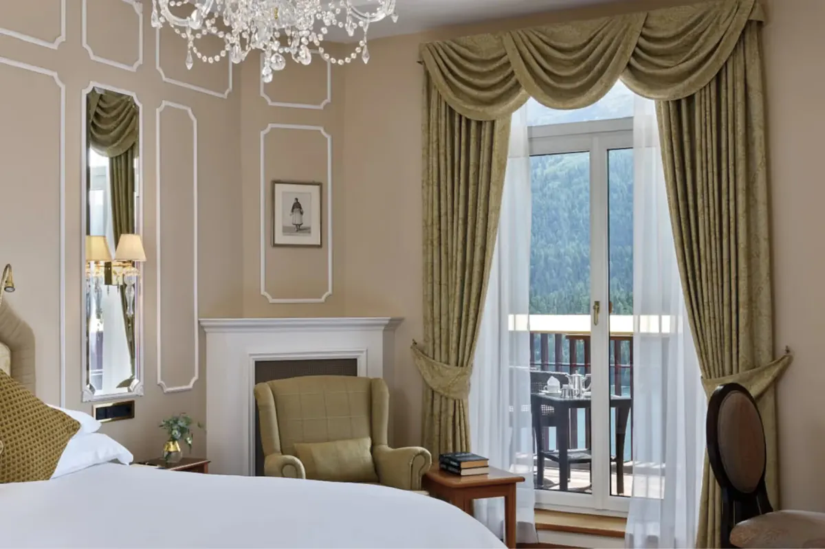 Suite with upholstered headboard, gold drapes, and full windows overlooking mountains