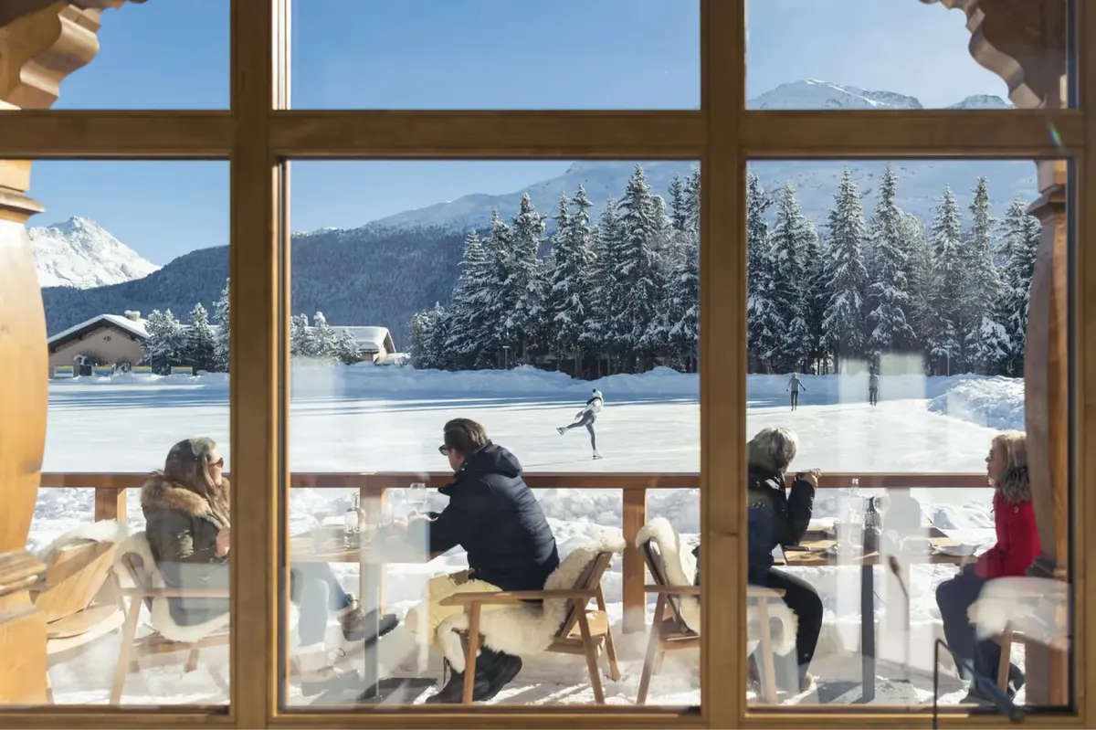 Guests enjoy drinks and lakeside views from the hotel’s terrace in winter sunlight