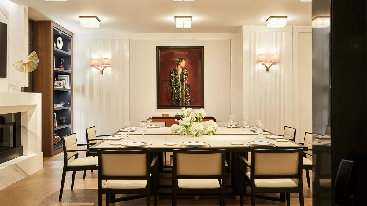 A private dining room with dark wood shelving, cream-colored chairs, and formal table setting
