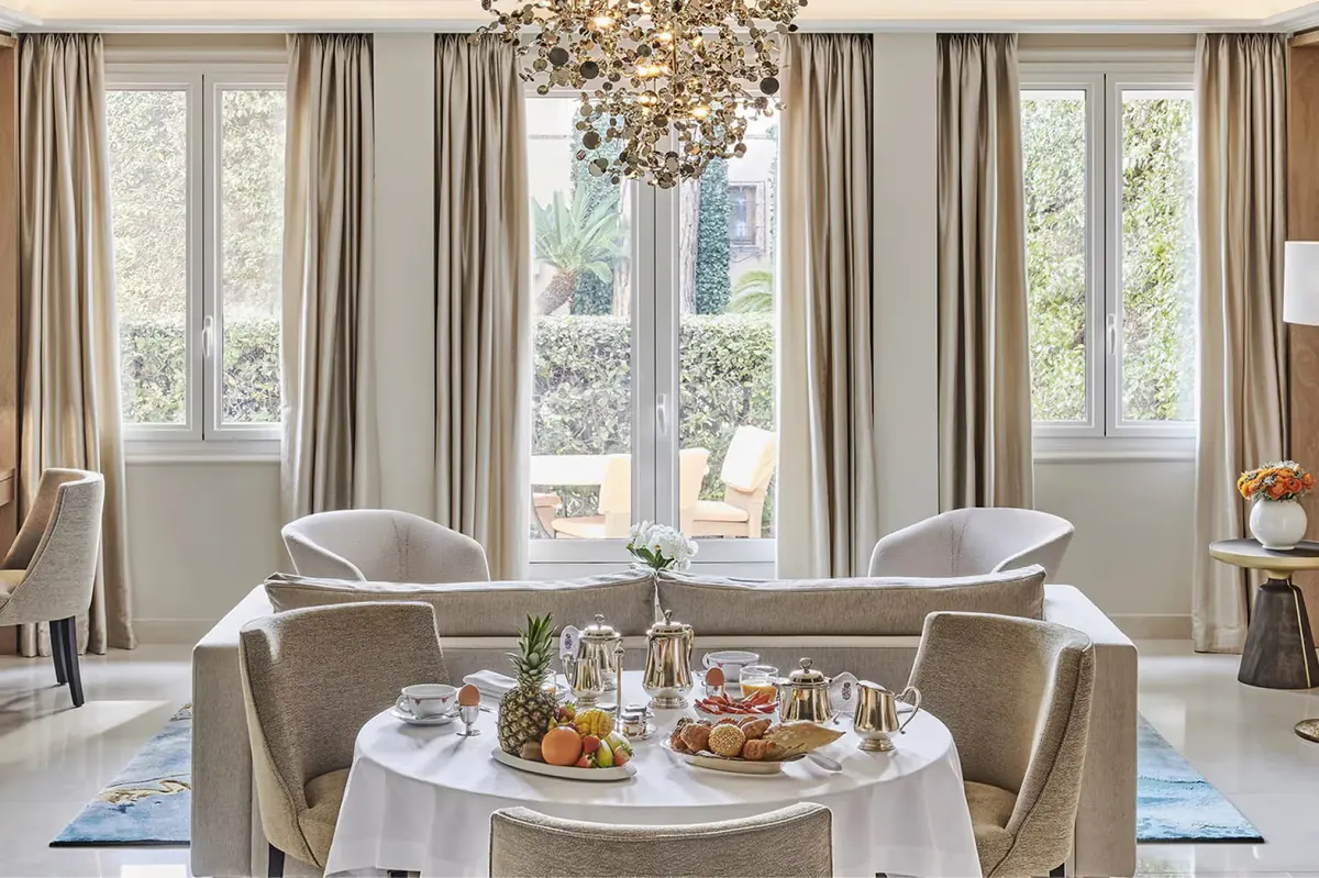Interior lounge with round table, large windows, and garden vistas