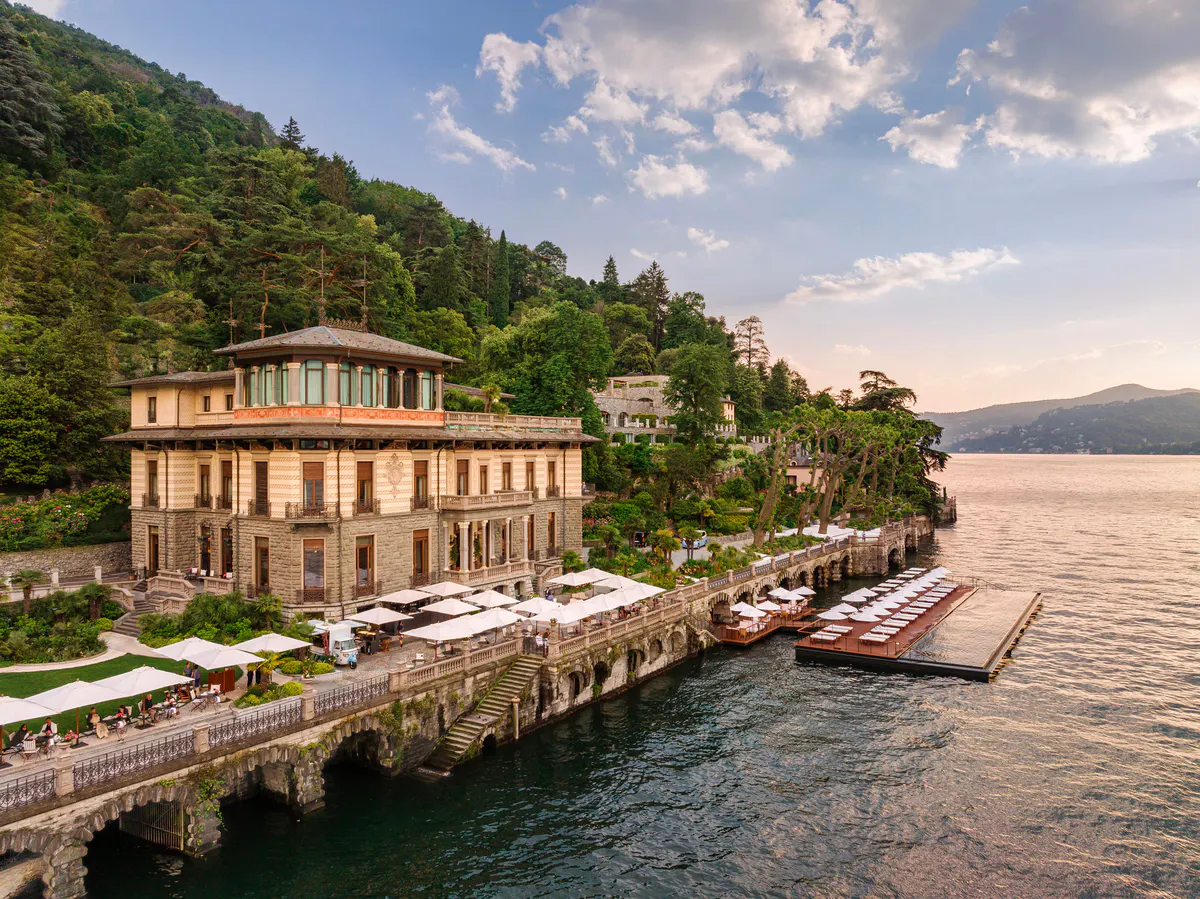 Neoclassical waterfront building with private dock and wooden boats moored in clear water