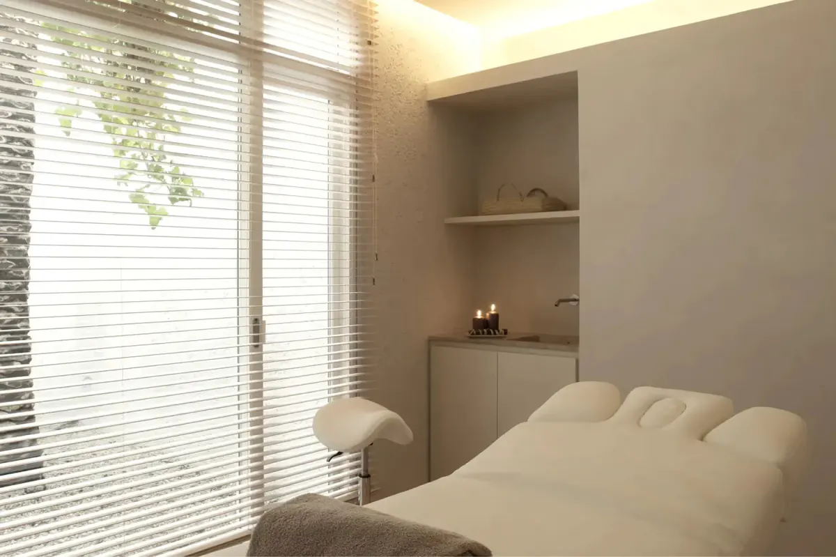 Spa treatment room with daybed, window blinds, and built-in shelving