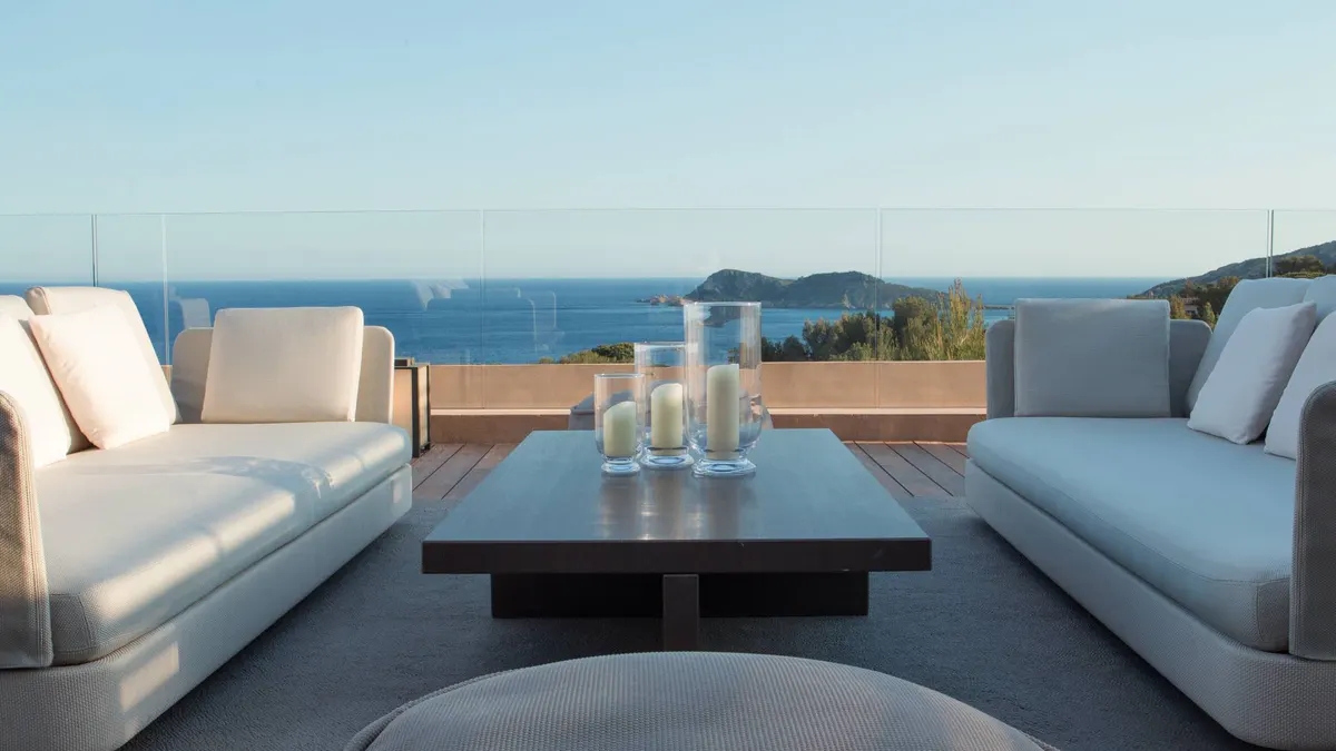 Two white lounges with gray pillows facing the sea