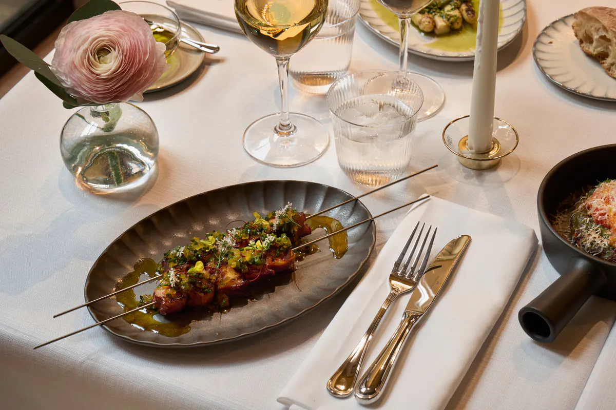 Plated dish with seasonal vegetables and delicate garnish paired with wine service