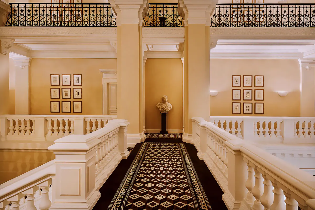 Grand lobby with wood paneling, potted palms, and cream-colored furnishings