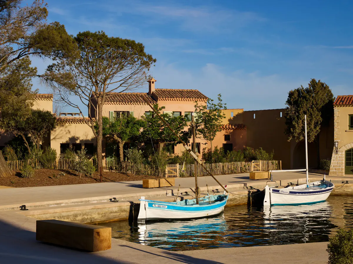 Traditional blue and white fishing boats moor at the quay before pastel harbor houses