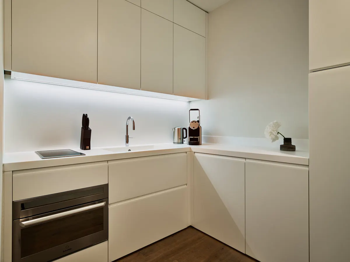 Compact kitchenette with minimalist cabinetry, white countertop, and integrated appliances