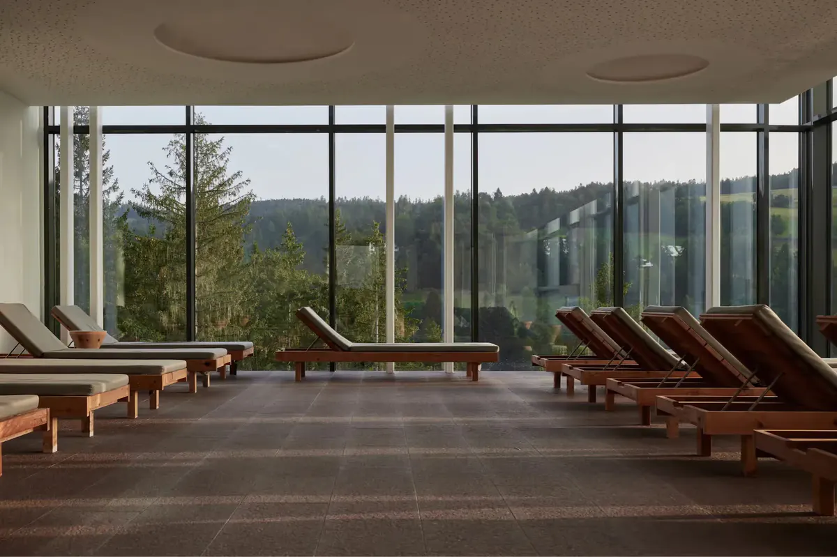 Spa relaxation room with wooden loungers and panoramic windows framing mountain views
