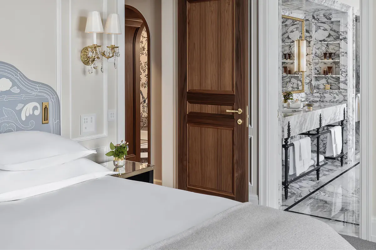 Hallway with white walls, wooden doors, and light stone flooring