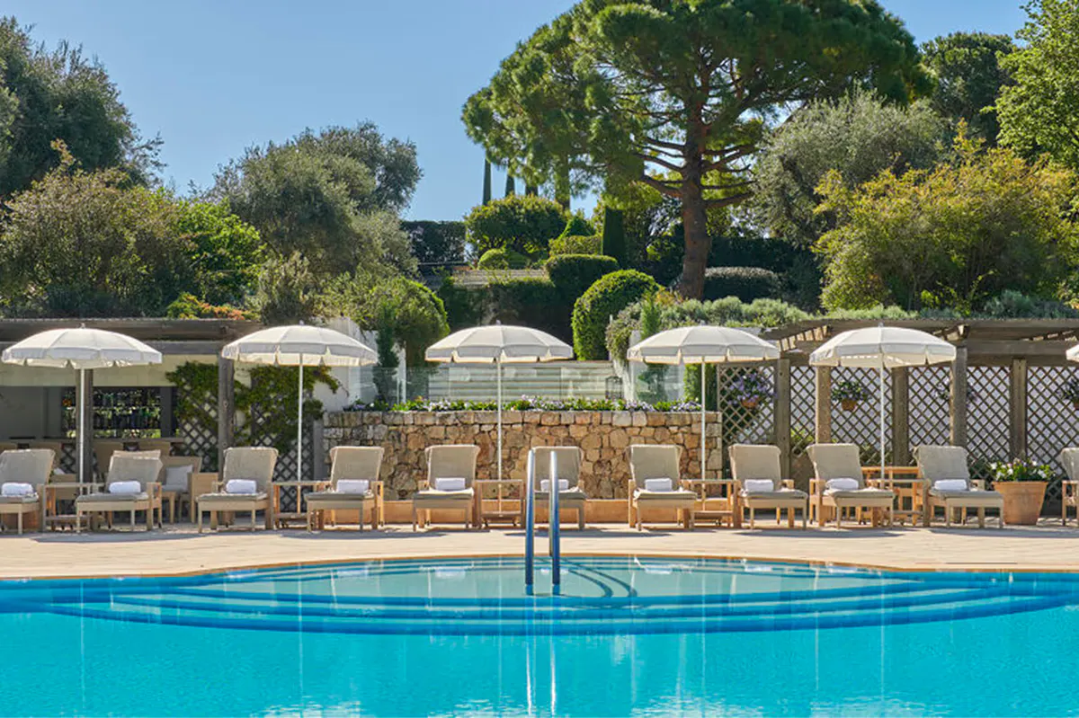 Pool terrace with white umbrellas and lounge chairs in landscaped gardens
