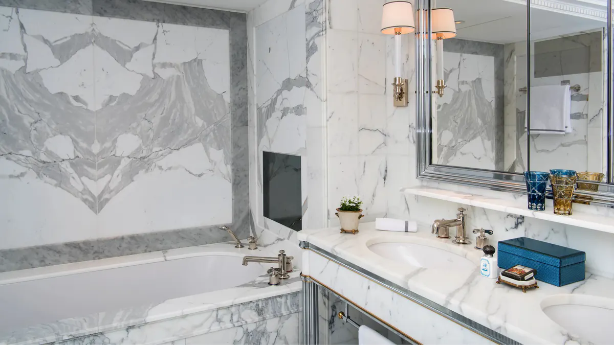 Suite with bed and dressing area, marble walls, and modern amenities in classical setting