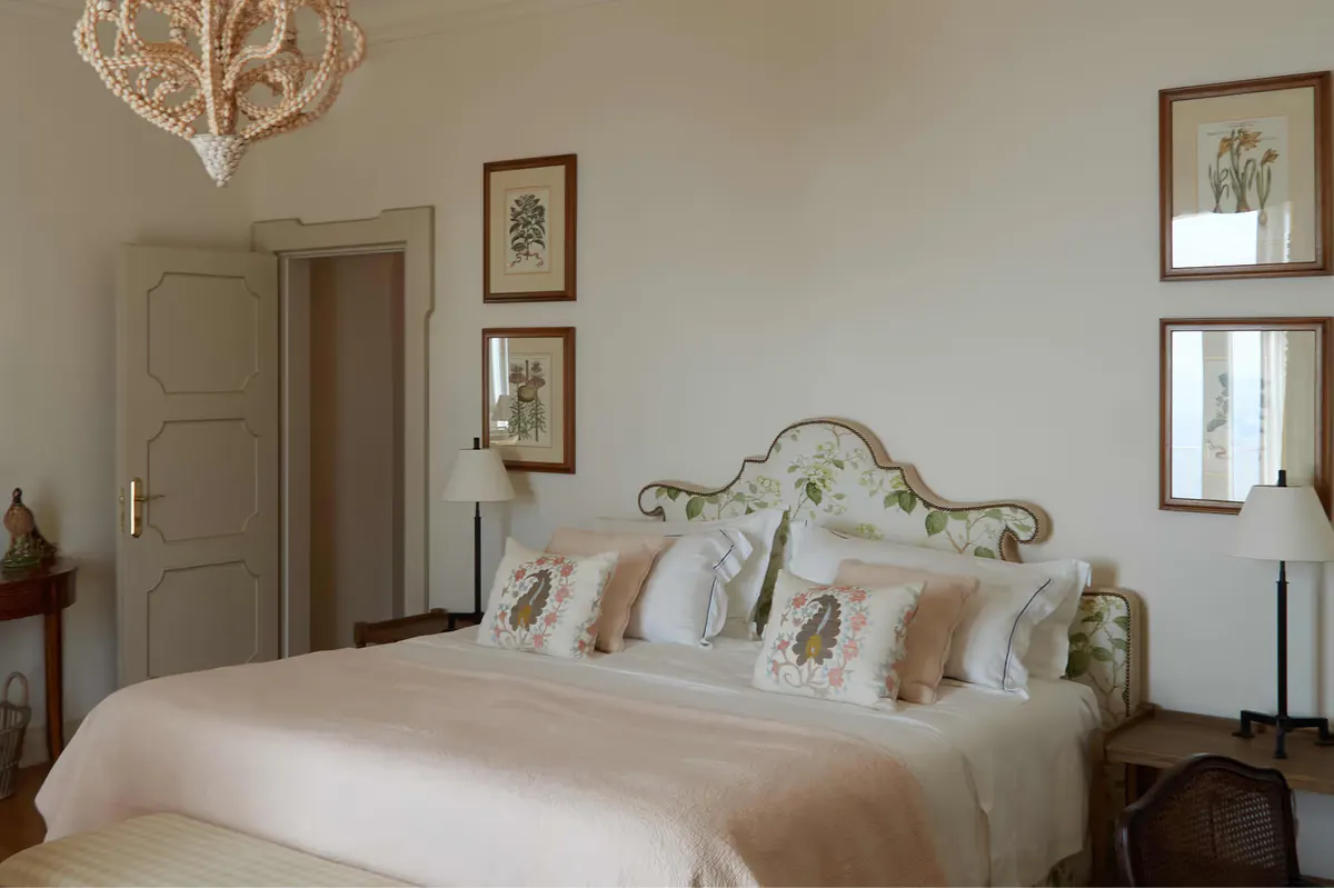 Bedroom with cream walls, ornate brass bed with patterned cushions, framed artwork, and arched niche