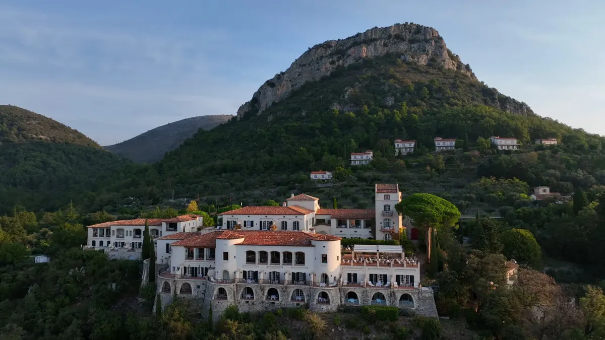 Hillside château with multi-story stone structures and terraced gardens