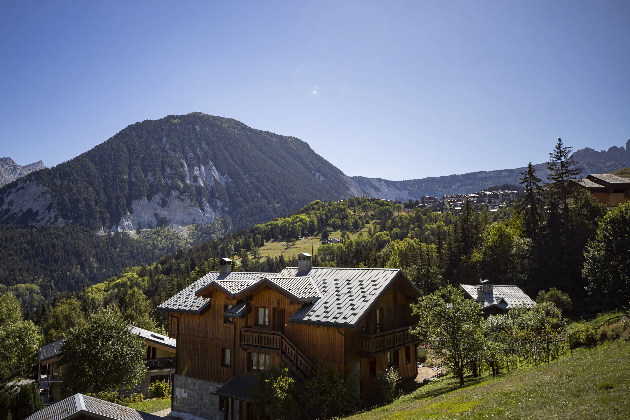 A timber chalet below green summer peaks at Courchevel