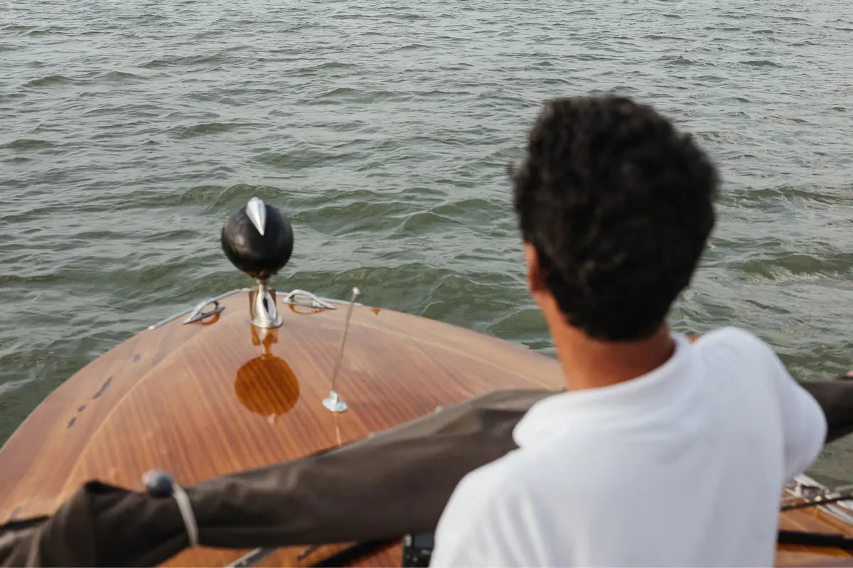 A person in a wooden boat on the Grand Canal, with a gondola pole visible against the water