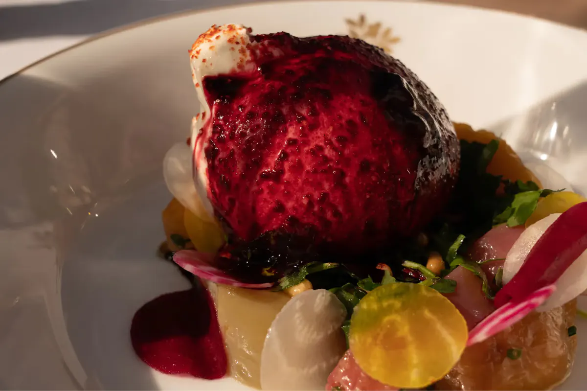 Artistic plated dish with dark berry mousse and candied garnish