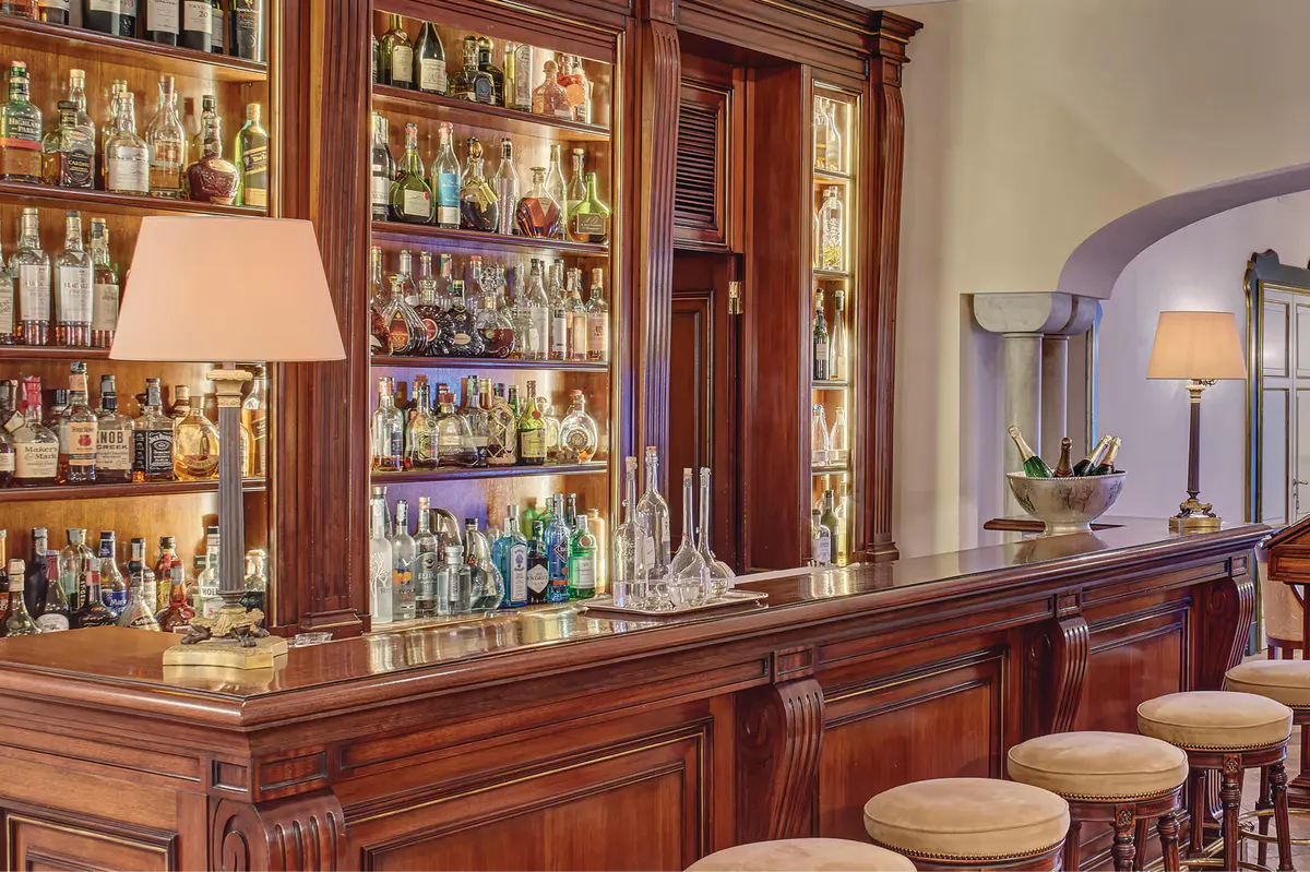 Mahogany bar counter with illuminated shelving displaying spirits and cocktail service area