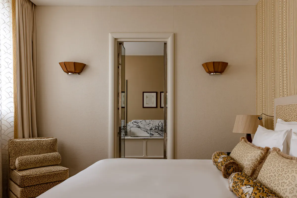 Bedroom interior with brass double bed, pale upholstery, and dark mirror detailing