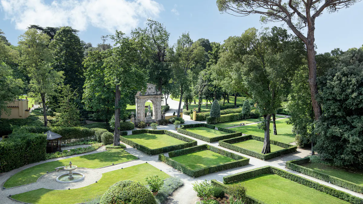 Manicured Renaissance gardens with geometric hedgerow paths, fountains, and mature shade trees